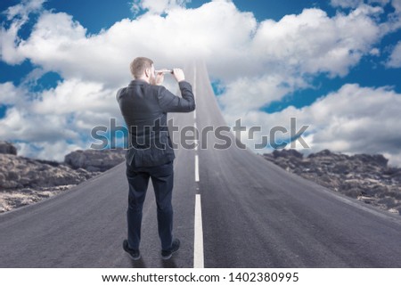 Businessman standing on road that goes up to the sky