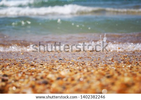 A crashing blue and green wave of water and sand on the ocean shore. Background for design with sea shells