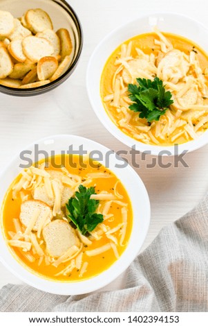 Pumpkin cream soup with croutons and fresh dill and parsley on wooden background, top view