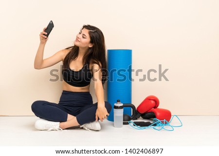 Teenager sport girl sitting on the floor making a selfie