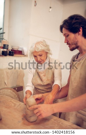 So concentrated. Nice aged woman focusing on her work while standing together with her apprentice
