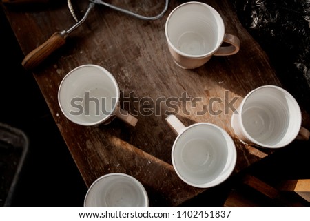 Cups made of clay handmade dishes, dishes from environmental materials. Wooden table on kitchen in cafe. Cups for coffee or tea. Cinema film picture. Sunlight on objects. Morning lights