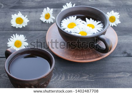 Cup of chamomile tea and chamomile flowers on wooden background. Close-up.