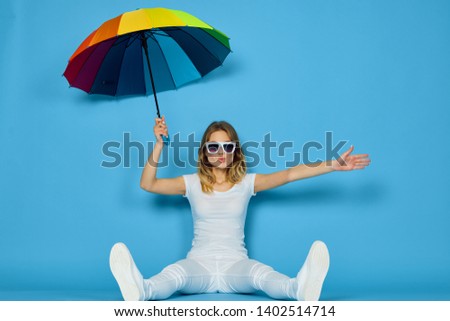 woman doll in glasses sits on the floor with an umbrella in glasses on a blue background                              