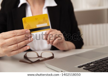 Closeup view of female hands holding yellow credit card. Shopping online concept.