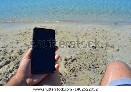 Looking to the smart phone on the beach.