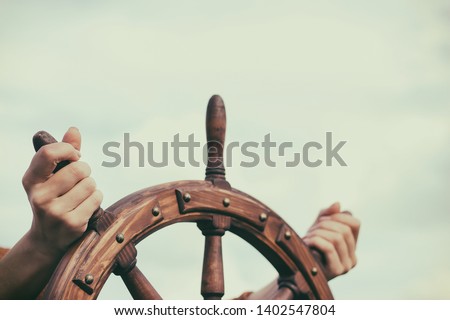 Steering hand wheel ship on sky background, hand hold hand wheel Royalty-Free Stock Photo #1402547804