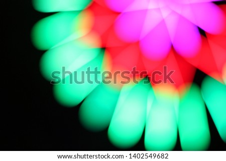 Multicolored bokeh that has a long, circular shape, like a starburst, with a black background.