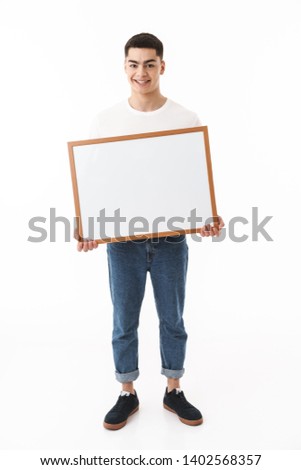 Happy young man standing isolated over white background, holding blank board