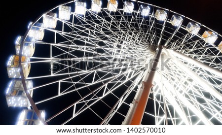 Beautiful photo of ferris wheel on city stret illuminated with white bulbs with night sky on the background