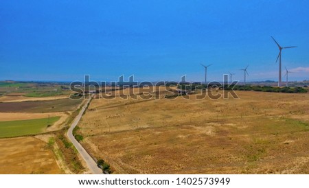 Aerial view of industrial windmills aligned in open countryside.