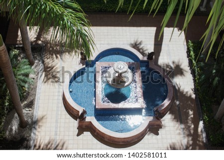 overhead view of a stone fountain. Multitiered fountain in a park with palm trees. Artistic fountain in a resort