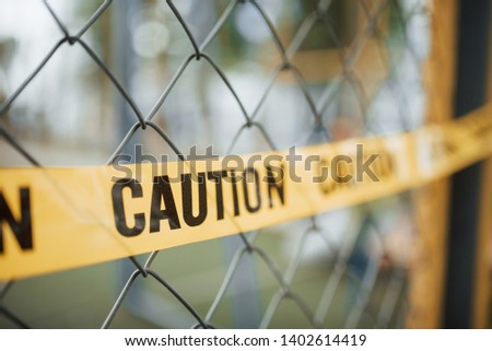 Do not enter. Yellow caution tape on the metal fence at daytime. Crime scene.