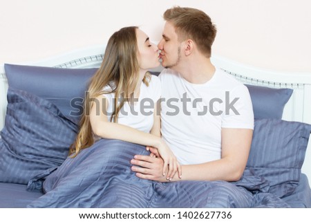 Beautiful loving couple kisses and hugging on bed in the morning.