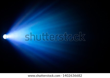beautiful blue color spotlight wide lens projector with light beam for film movie and cinema at night . abstract smoke texture . screening for multimedia . black background .