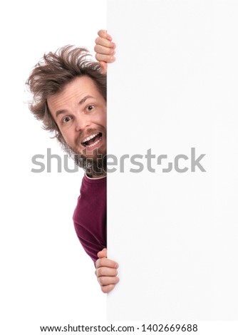Crazy bearded Man with funny Haircut showing empty blank signboard with copy space. Smiling guy peeking out from behind big white banner, isolated on white background.