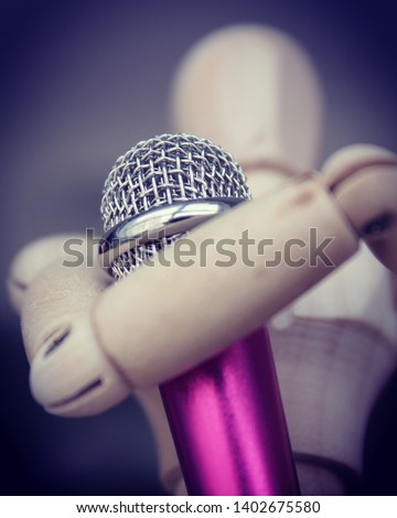 A wooden figure or toy holding a microphone to show that it is giving a speach, the picture has a low angle to show strength and power, because words are stronger than any thing.