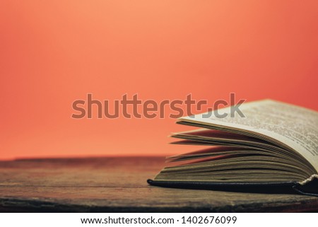 Open book on a  old wooden round table. beautiful coral orange background.