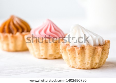Small cakes with cream on a white table. Selective focus. Front view.
