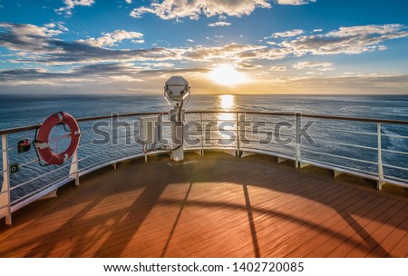 Wooden deck and railing from cruise ship. Beautiful sunset and ocean view. Royalty-Free Stock Photo #1402720085