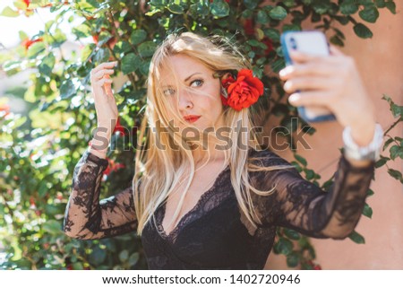 Beautiful Scandinavian blonde woman having a problem with her hair while making selfie with smartphone
