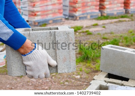 Worker loads cinder blocks  from cement slurry for construction on the  warehouse outdoor