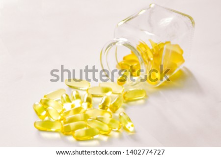 from a glass jar scattered yellow capsules,