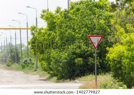 Road sign give way on the background with trees