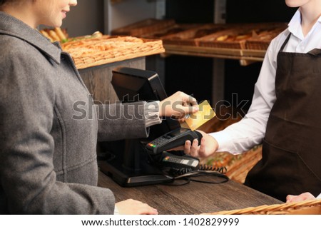 Woman with credit card using payment terminal at shop