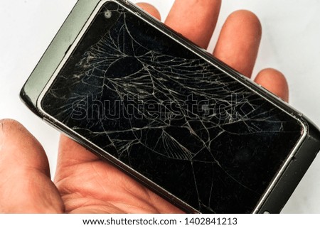 Male hand is holding a broken cell phone. Broken touch screen in man's hand. Cracked, damaged phone. human hand.
