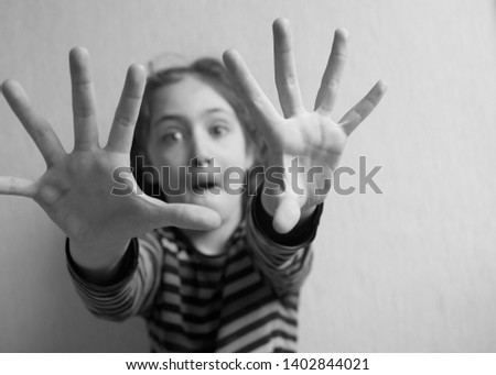 Little girl defends herself with open palms her face is out of focus