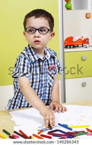 Little boy wearing glasses and draw with crayons