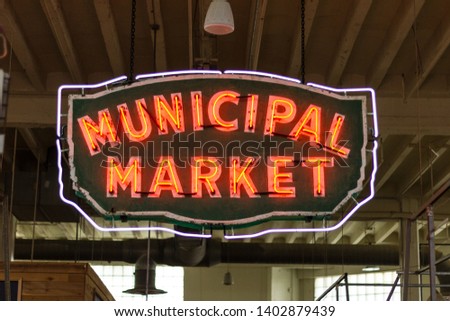 Neon sign hanging from a ceiling in a public market during the day