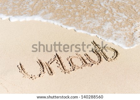 High angle view of word Urlaub written on sand by water surf