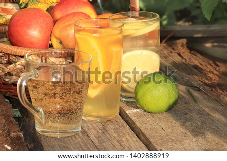 Summer drinks in the garden on an old table with dandelions. Apple and lemon juices on an old wooden background, a basket with apples and dandelions