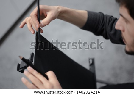Close-up of young man painting with pencil on easel