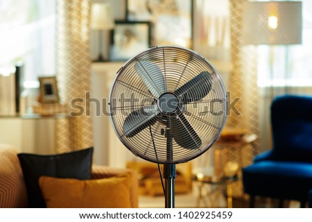 Closeup on electric floor standing fan in the modern living room in sunny hot summer day. Royalty-Free Stock Photo #1402925459