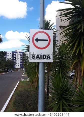 Signage plate, galvanized steel, electrostatic painting, reflective adhesive, indicating with arrow, the following direction, urban landscape in the Brazilian capital with blue sky and white clouds.