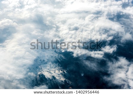 Top view of white clouds above the ground or water. Horizontal frame