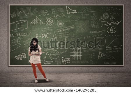 Asian female student is standing on written blackboard