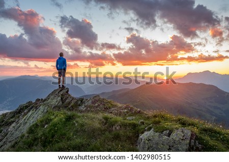 Man watching dramatic sunset in the mountains Royalty-Free Stock Photo #1402980515