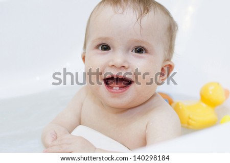 Baby girl having big bath with toys