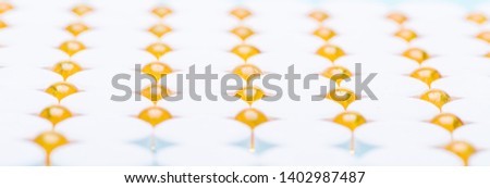 Omega 3 fish oil capsules on white background.Blue background on which are white and yellow pills. Background of medications extending into the distance in defocus.