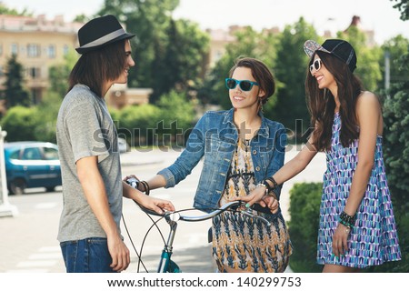 Two girls communicate with a guy. Outdoors