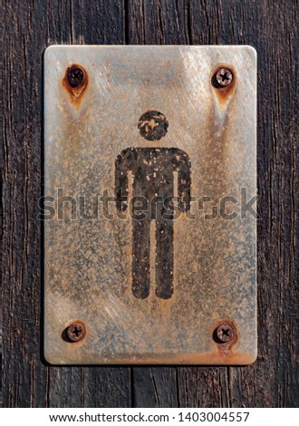 Gentleman toilet sign in old and rustly metallic plate on wooden surface