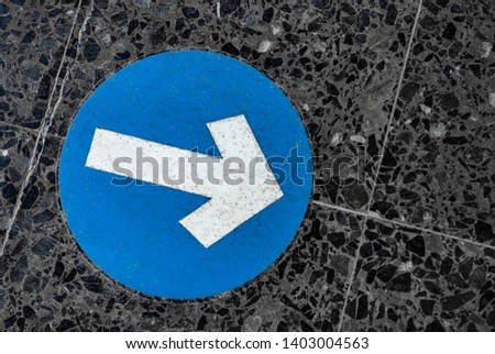 Blue round traffic road sign with white arrow symbol pointing right