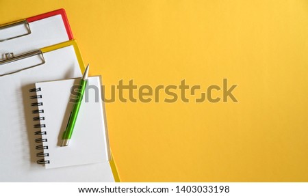 Clipboards, memo pad and green pen on yellow top or desk background. Copy Space