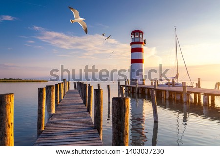 Lighthouse at Lake Neusiedl at sunset near Podersdorf with sea gulls flying around the lighthouse. Burgenland, Austria Royalty-Free Stock Photo #1403037230