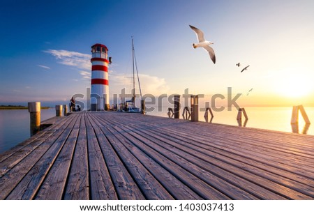 Lighthouse at Lake Neusiedl at sunset near Podersdorf with sea gulls flying around the lighthouse. Burgenland, Austria Royalty-Free Stock Photo #1403037413