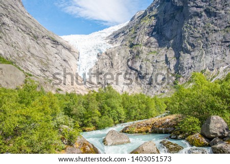 Norwegian landscape with milky blue glacier river, glacier and green mountains. Briksdal or Briksdalsbreen glacier in Olden, Norway. 